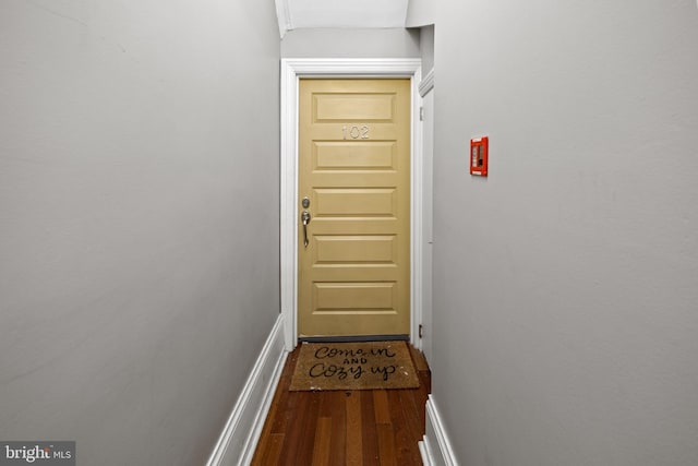 doorway featuring dark wood-type flooring and baseboards