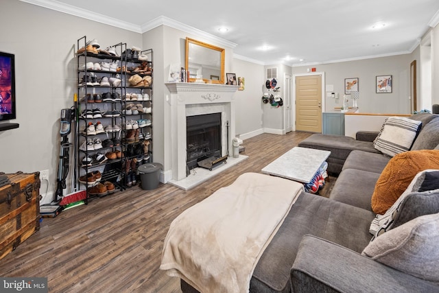 living area featuring recessed lighting, a fireplace with raised hearth, ornamental molding, and wood finished floors