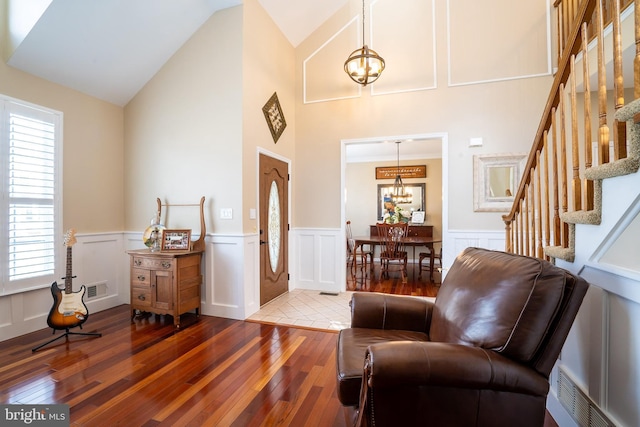 sitting room featuring visible vents, hardwood / wood-style flooring, stairway, lofted ceiling, and a chandelier