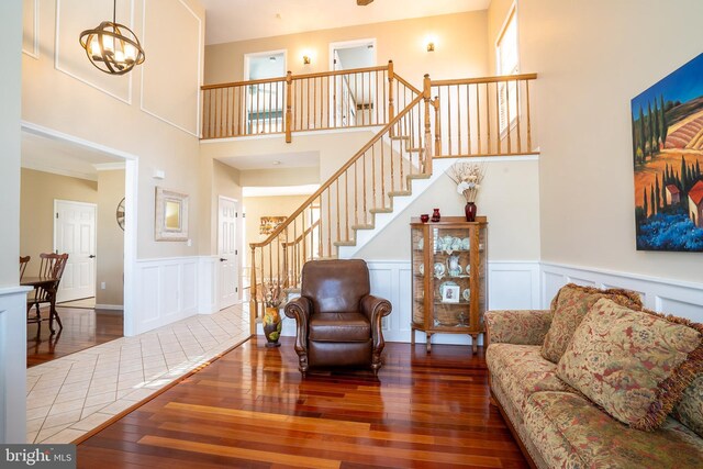 living room featuring stairs, a decorative wall, a notable chandelier, and wood-type flooring