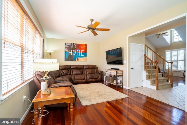 living area featuring baseboards, wood-type flooring, a ceiling fan, and stairs