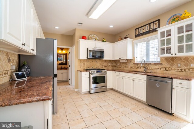 kitchen featuring light tile patterned floors, white cabinetry, stainless steel appliances, and a sink