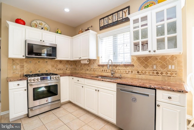 kitchen with a sink, stainless steel appliances, stone countertops, and white cabinets