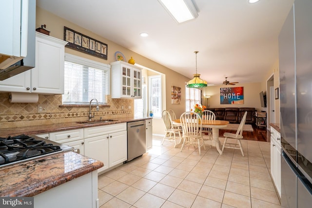 kitchen featuring backsplash, light tile patterned floors, appliances with stainless steel finishes, white cabinets, and a sink