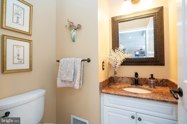 bathroom with vanity, toilet, and visible vents