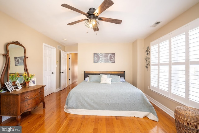 bedroom with visible vents, a ceiling fan, baseboards, and hardwood / wood-style floors