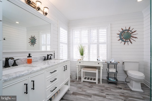 full bath featuring toilet, crown molding, and a sink