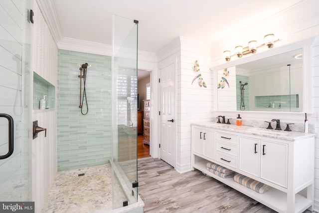 bathroom with double vanity, a stall shower, crown molding, and a sink