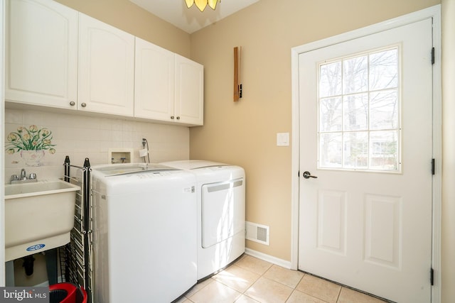 washroom featuring visible vents, washer and dryer, a sink, cabinet space, and light tile patterned flooring