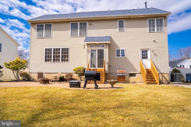 rear view of property featuring entry steps, a patio, a yard, and an outdoor fire pit