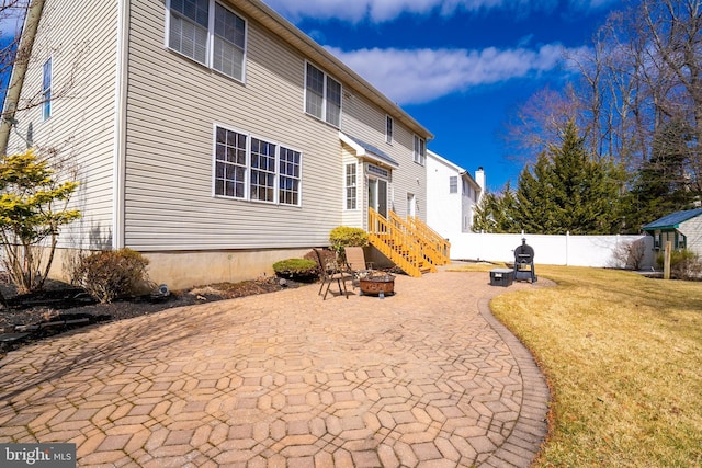 back of house with fence, a lawn, a patio, and an outdoor fire pit