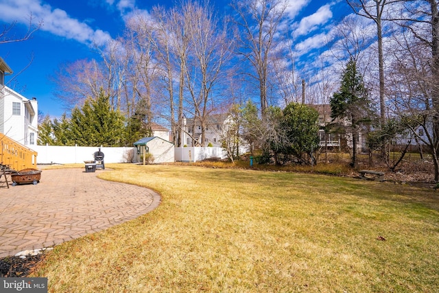 view of yard featuring a patio, an outdoor fire pit, a fenced backyard, an outdoor structure, and a storage unit