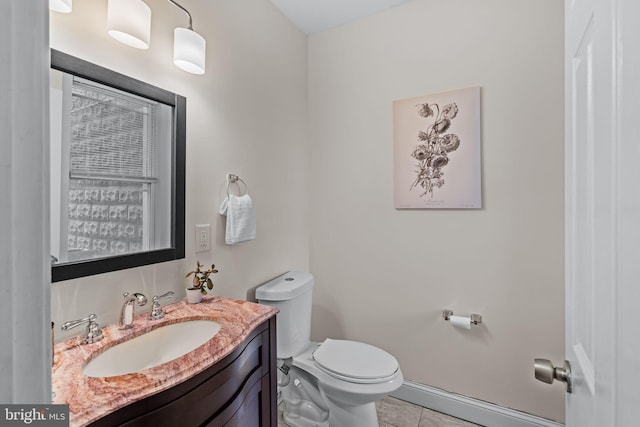 half bath with tile patterned flooring, baseboards, vanity, and toilet