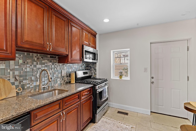 kitchen with tasteful backsplash, visible vents, stainless steel appliances, stone counters, and a sink