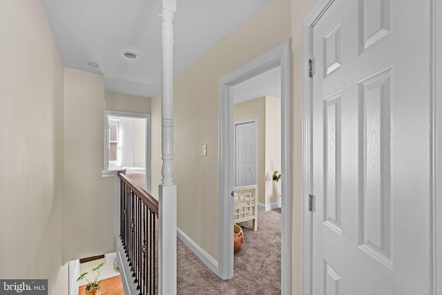 corridor featuring baseboards, carpet flooring, and an upstairs landing