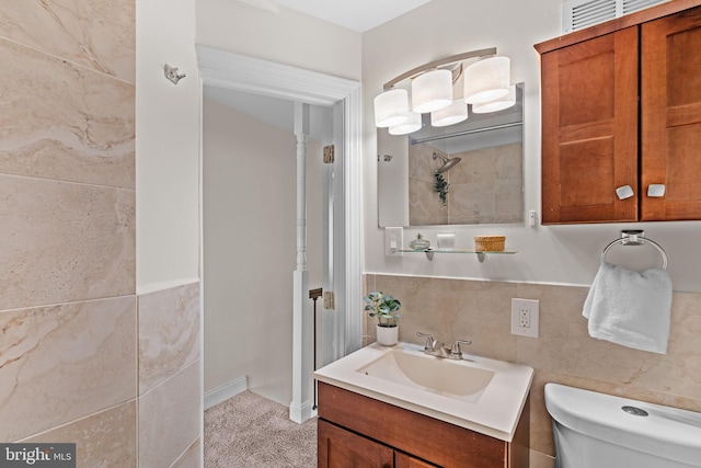 bathroom featuring toilet, backsplash, vanity, and tile walls