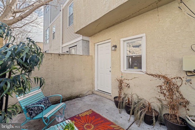 doorway to property with fence, a patio, and stucco siding