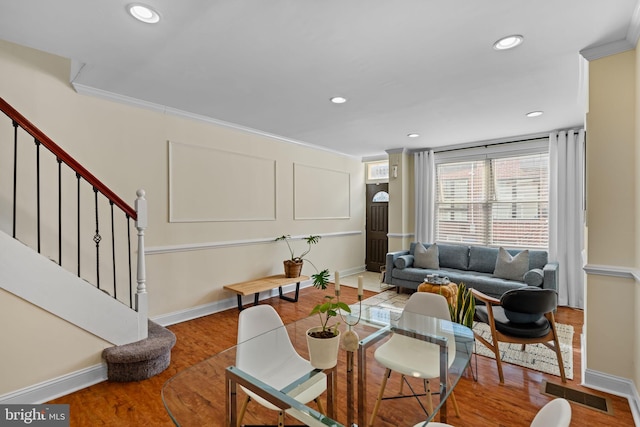 living room with stairs, visible vents, wood finished floors, and ornamental molding