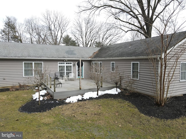 rear view of property featuring a yard, a shingled roof, and a patio