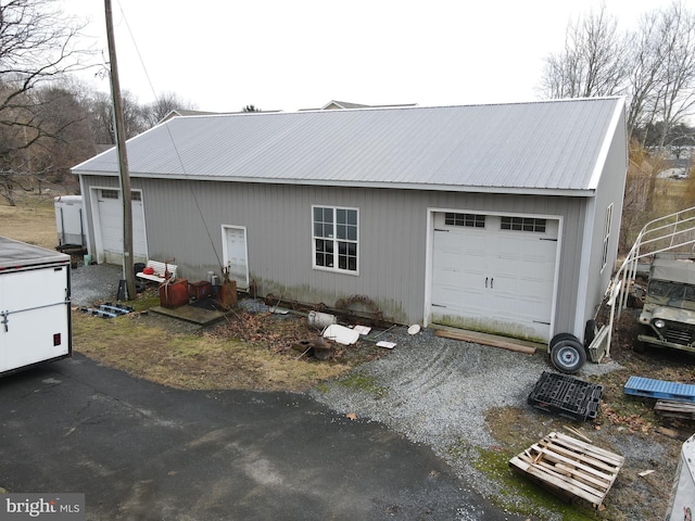 exterior space with a garage, metal roof, and an outbuilding