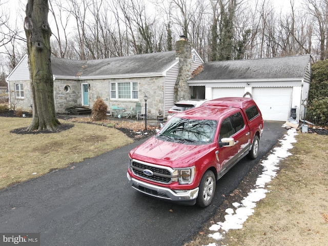 ranch-style home with a garage, stone siding, a chimney, and roof with shingles