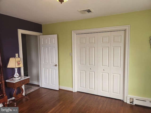 bedroom with dark wood-style flooring, baseboard heating, visible vents, and baseboards