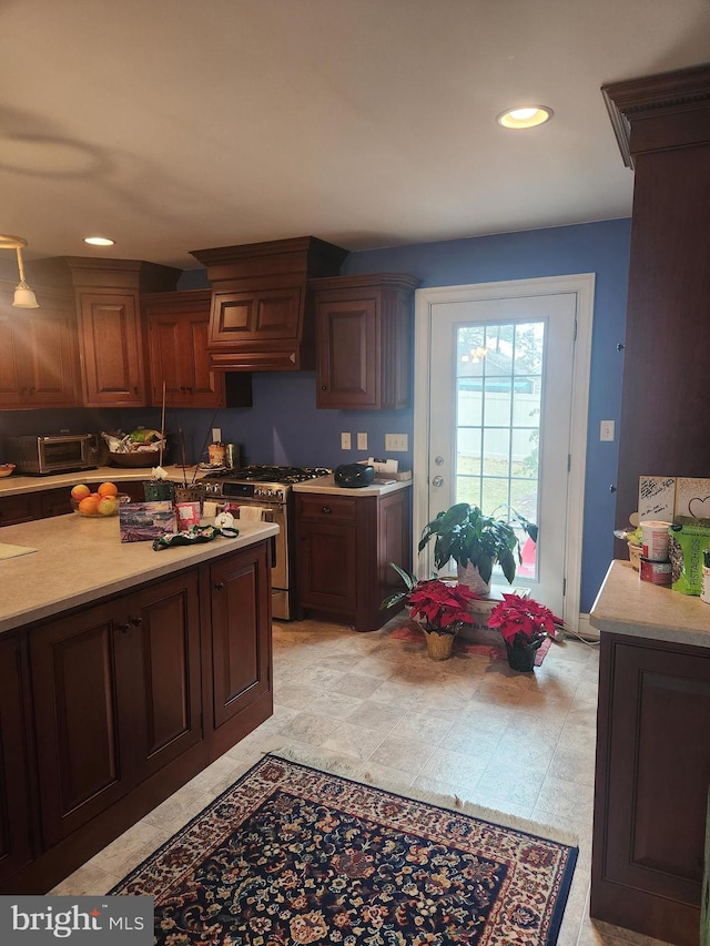 kitchen with gas range, custom exhaust hood, light countertops, and recessed lighting