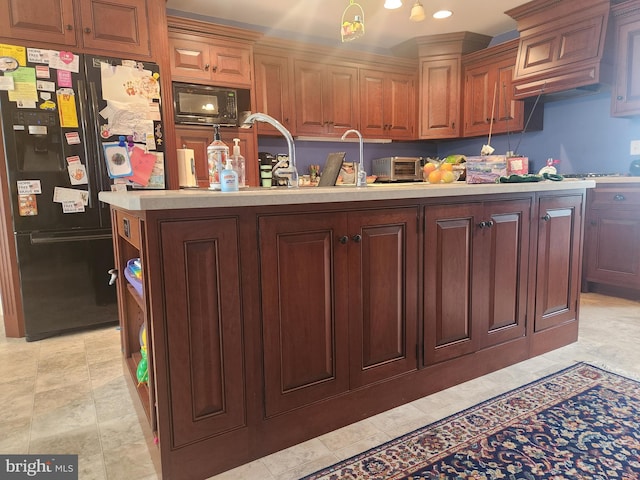 kitchen featuring black appliances, a toaster, a kitchen island with sink, and light countertops