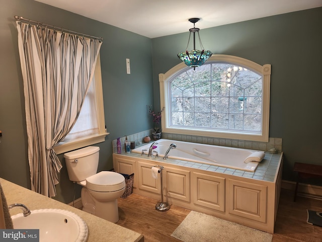 full bath featuring toilet, wood finished floors, a sink, and a bath