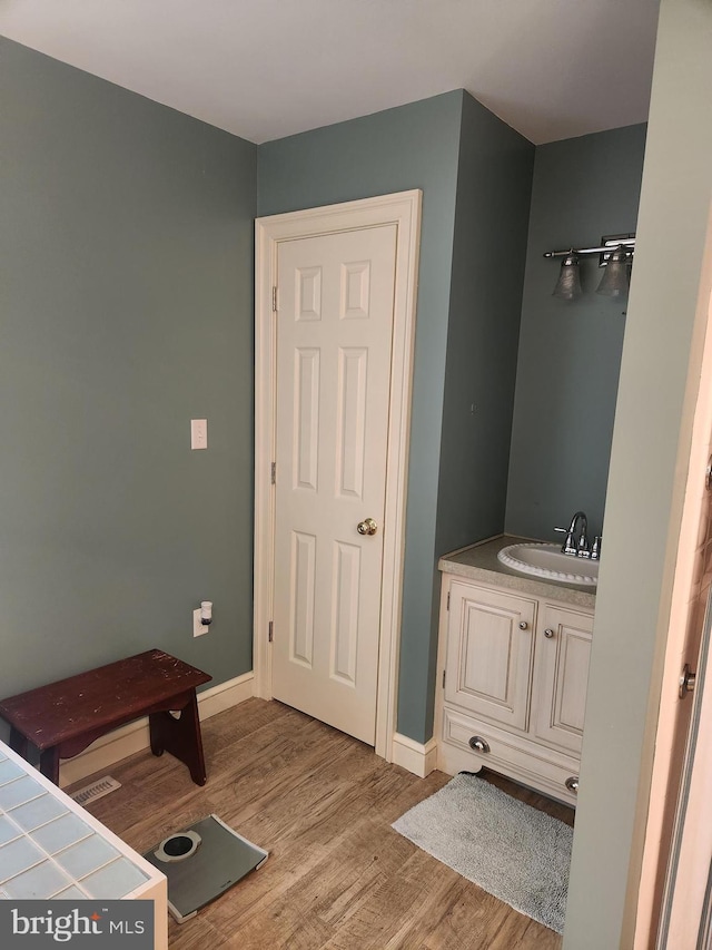 bathroom featuring vanity, baseboards, and wood finished floors