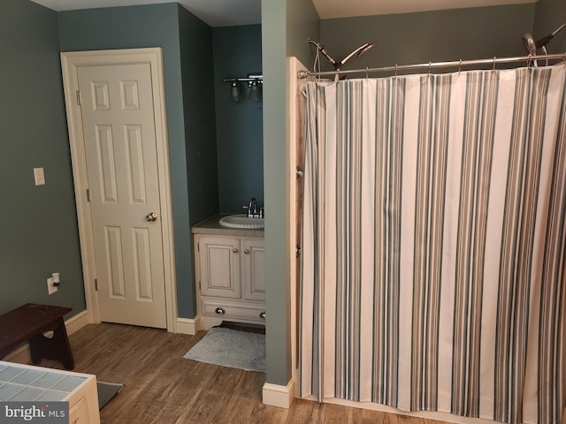 bathroom featuring vanity, baseboards, wood finished floors, and a shower with shower curtain