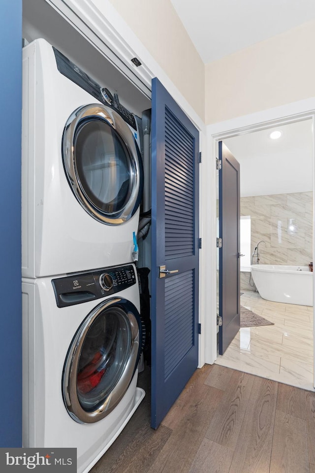 laundry area with laundry area, stacked washing maching and dryer, and wood finished floors