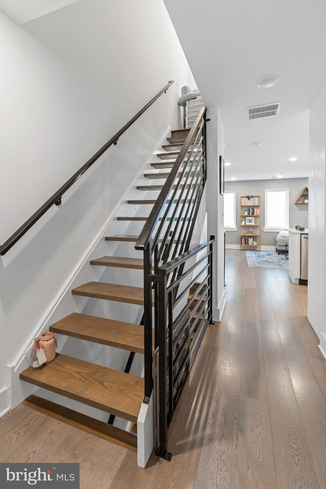 stairway featuring wood-type flooring, visible vents, and baseboards