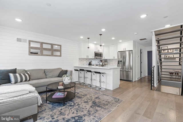 living area featuring light wood-style floors, stairway, visible vents, and recessed lighting