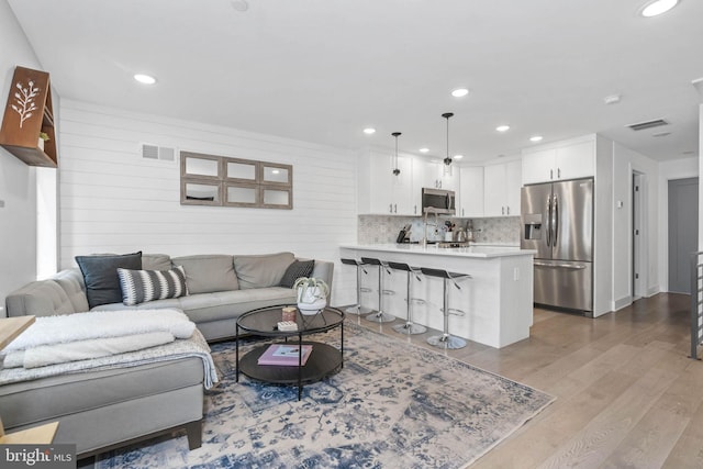 living room with visible vents, wood finished floors, and recessed lighting