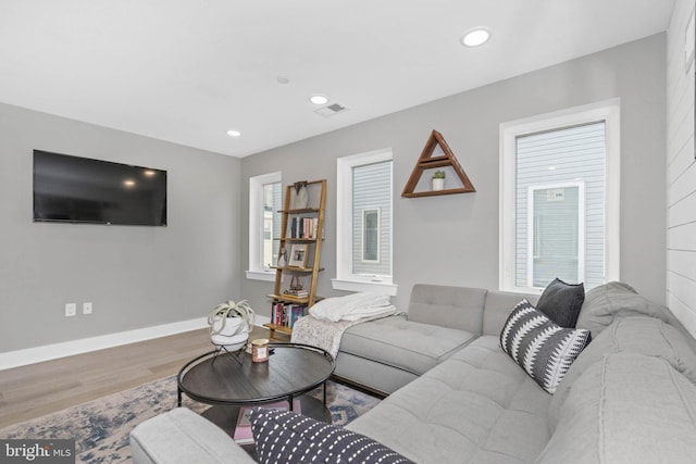 living room featuring visible vents, baseboards, wood finished floors, and recessed lighting