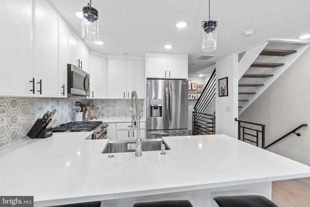 kitchen with decorative light fixtures, a breakfast bar area, tasteful backsplash, light countertops, and appliances with stainless steel finishes