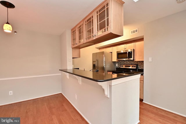 kitchen with visible vents, appliances with stainless steel finishes, dark countertops, light wood-type flooring, and backsplash