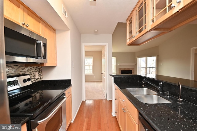 kitchen featuring visible vents, a sink, tasteful backsplash, appliances with stainless steel finishes, and a fireplace