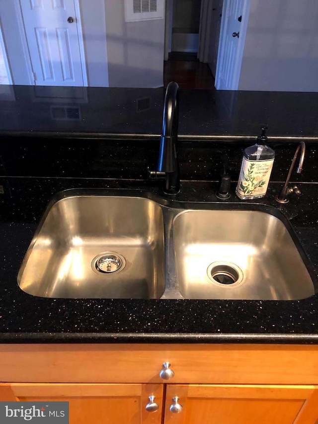 room details featuring dark stone counters and a sink