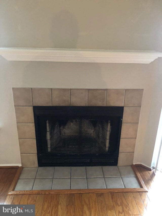 interior details with a tile fireplace, baseboards, and wood finished floors