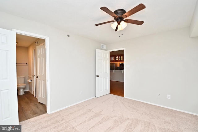 unfurnished bedroom featuring visible vents, connected bathroom, baseboards, carpet flooring, and a ceiling fan