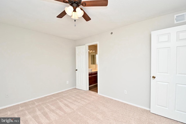 unfurnished bedroom with ensuite bath, baseboards, visible vents, and carpet floors