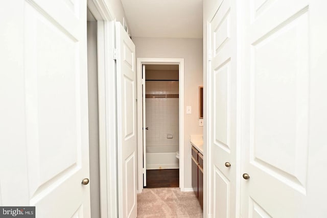 hall featuring baseboards and light colored carpet