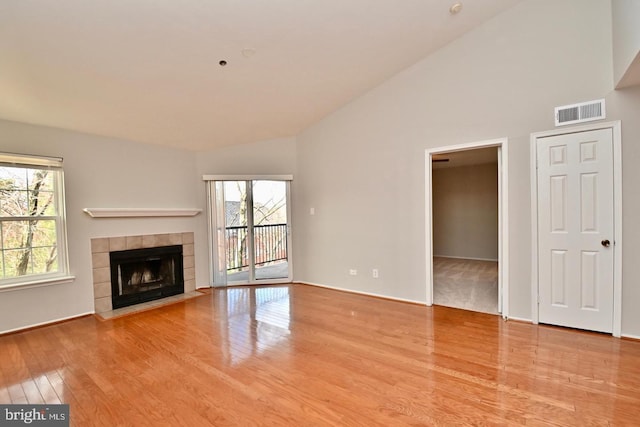 unfurnished living room featuring a fireplace, wood finished floors, visible vents, and high vaulted ceiling