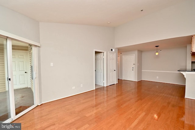 unfurnished living room featuring light wood finished floors and high vaulted ceiling