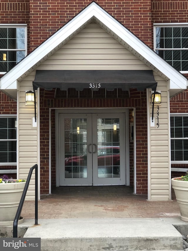 entrance to property featuring french doors and brick siding