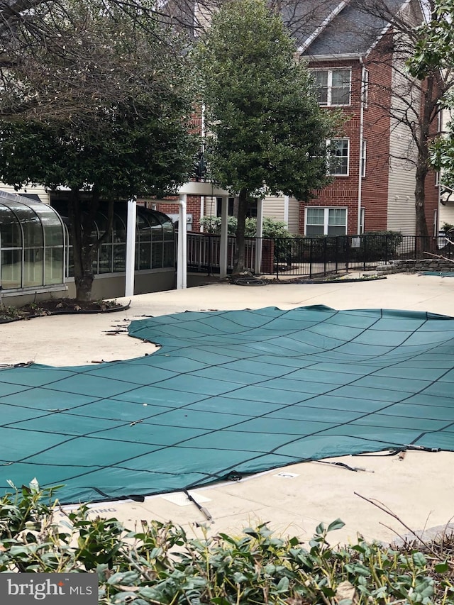 community pool featuring a patio area, a sunroom, and fence