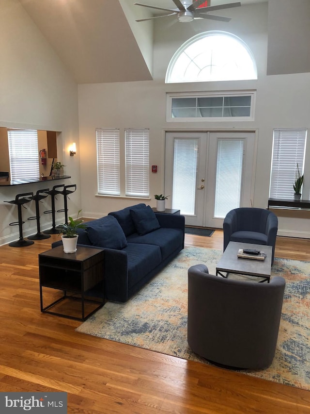 living area featuring high vaulted ceiling, wood finished floors, french doors, baseboards, and ceiling fan