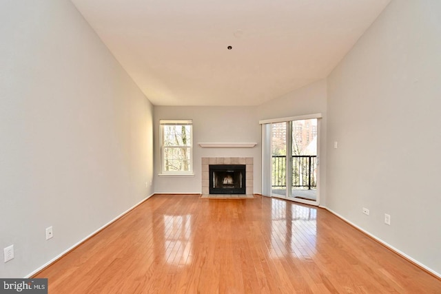 unfurnished living room featuring baseboards, plenty of natural light, light wood-style flooring, and a tile fireplace